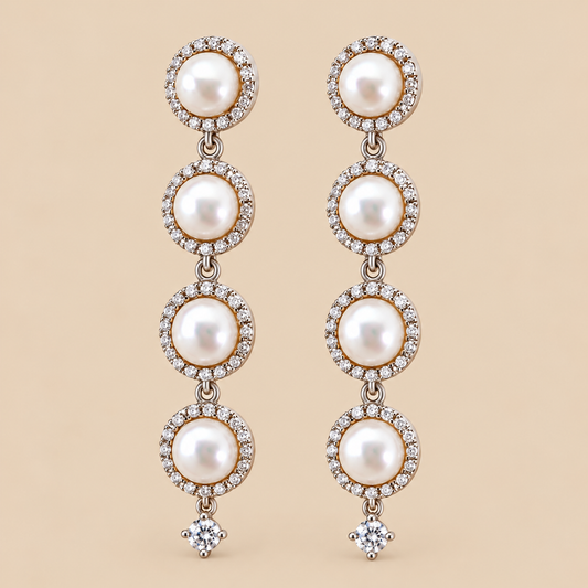 A pair of long drop earrings featuring four stacked white pearls in circular settings surrounded by small clear stones, with a single clear round-shaped stone dangling below each earring, shown on a solid beige background.