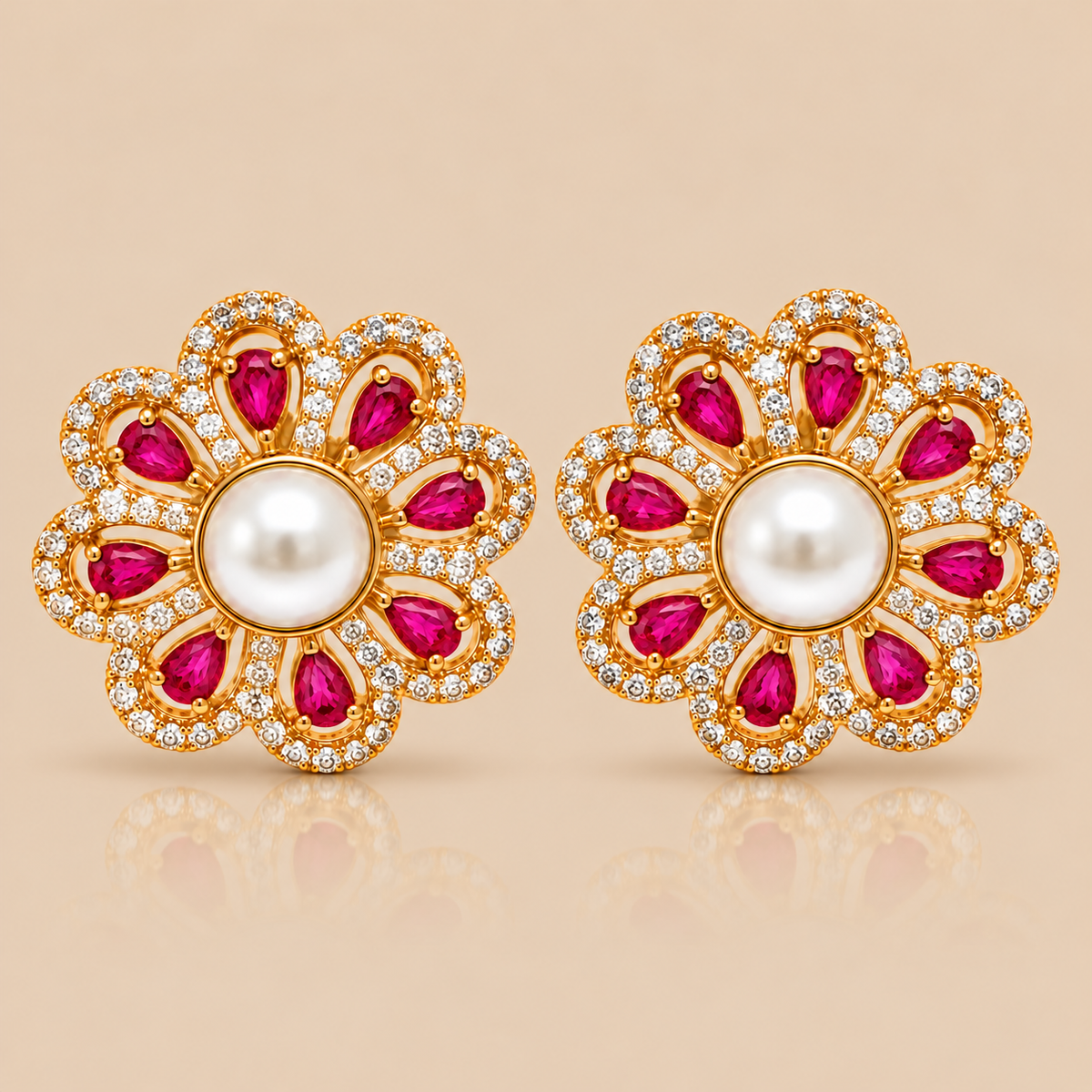 A pair of gold flower-shaped stud earrings with white pearl centers, surrounded by rows of small clear stones and bright pink teardrop-shaped gemstones, shown on a warm beige background.
