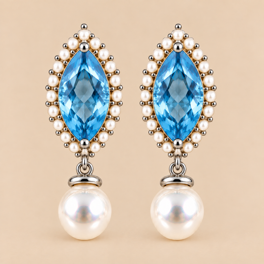 A pair of drop earrings featuring marquise-cut swiss blue topaz surrounded by small white pearls and silver-toned beads, with round white pearl drops below, set against a solid beige background.