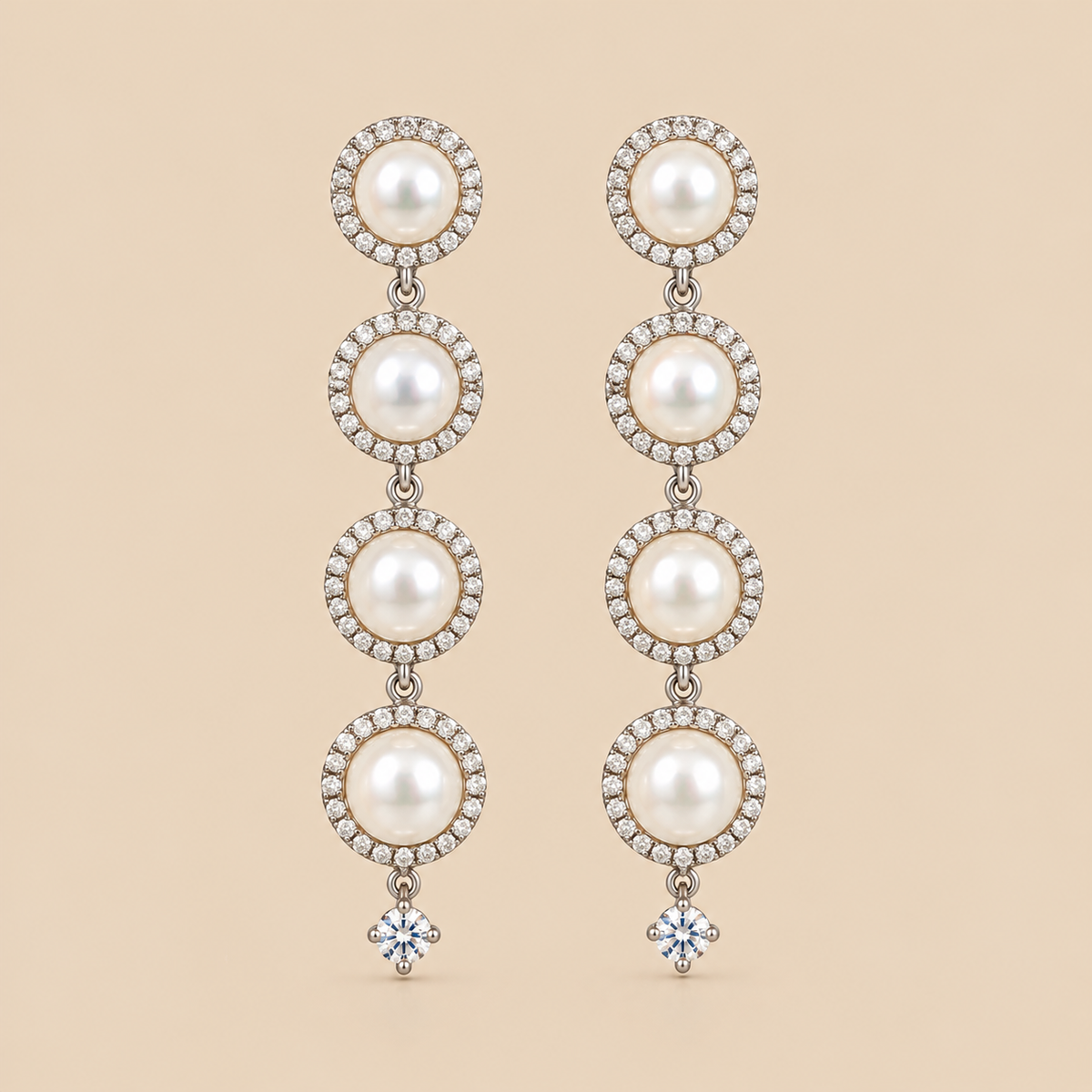 A pair of long drop earrings featuring four stacked white pearls in circular settings surrounded by small clear stones, with a single clear round-shaped stone dangling below each earring, shown on a solid beige background.