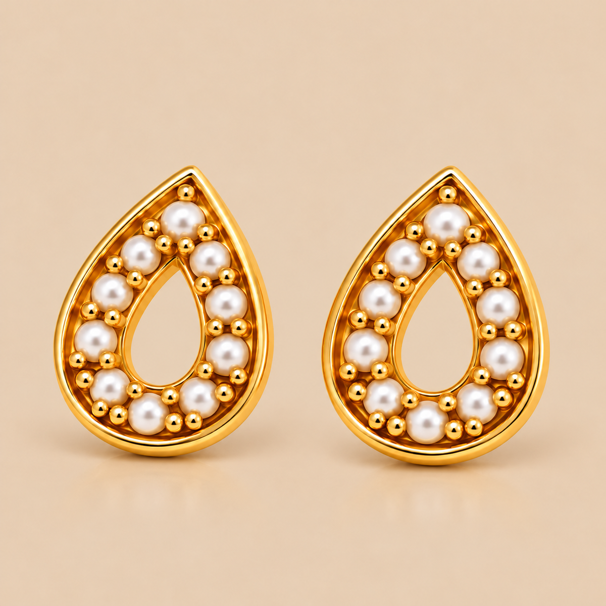 A pair of gold teardrop-shaped earrings with white pearl accents, displayed on a warm beige background .